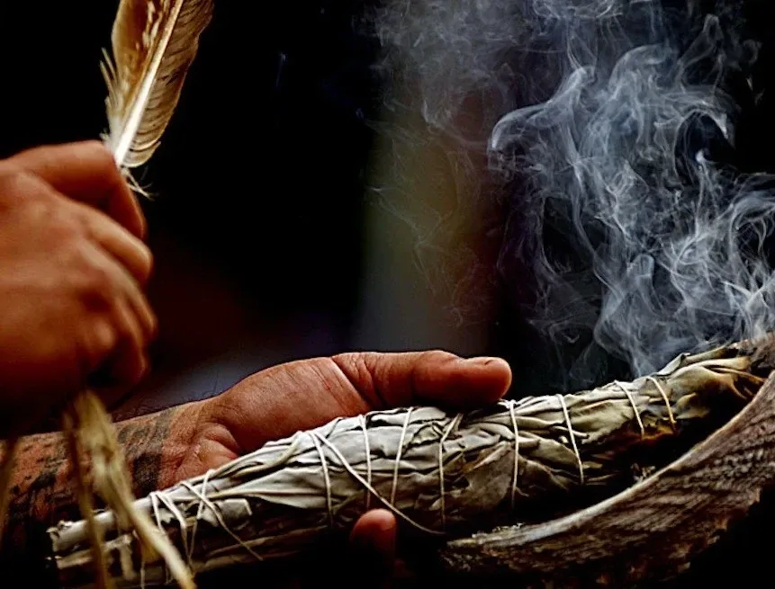 Hand holding burning sage, a traditional smudge stick